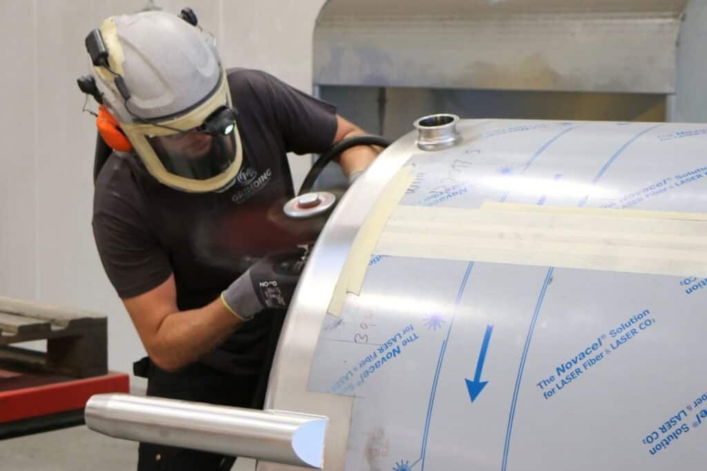 Worker polishing stainless steel tank for beverage production – M&A Steel Group