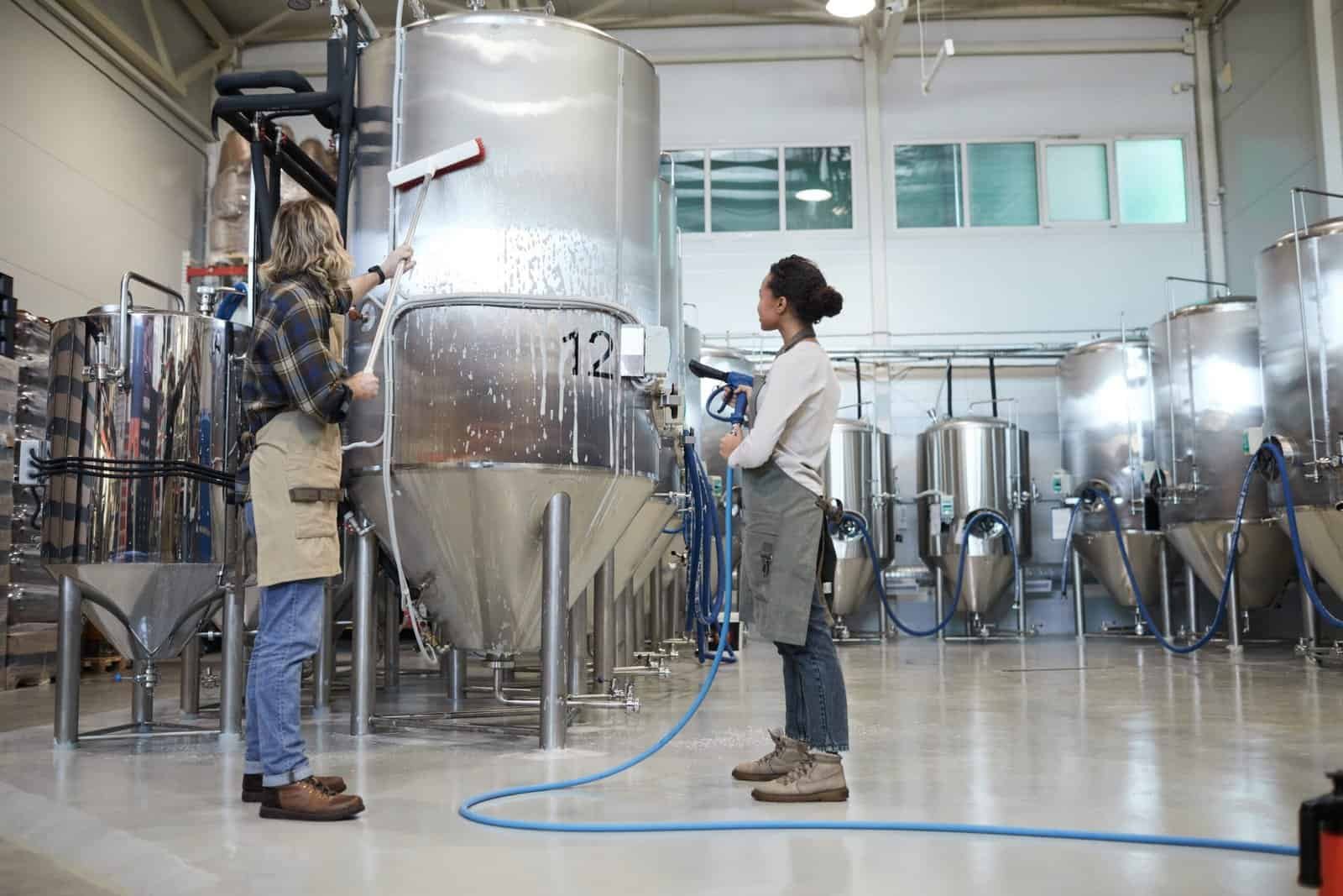 Wide angle view at two workers washing equipment at modern industrial brewery, copy space